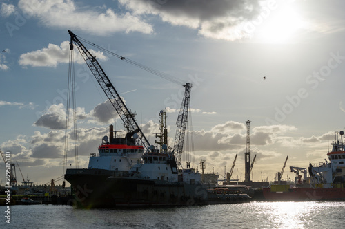 Setting sun in the port of Rotterdam, the Netherlands, Europe. Ships and cranes.