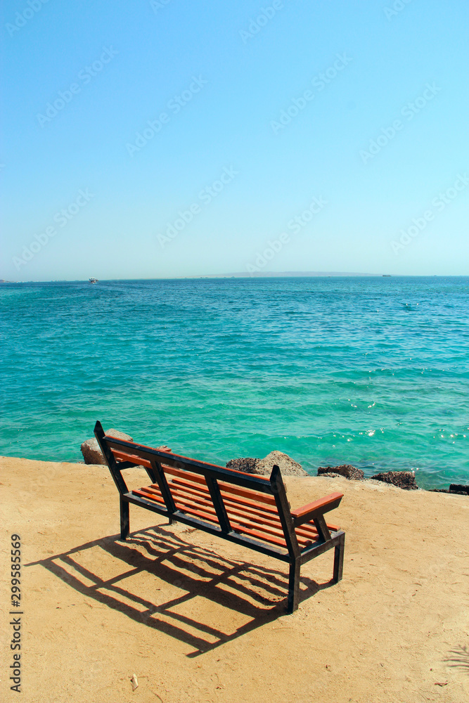 Empty bench near coastline at tropical resort. Exotic relaxation