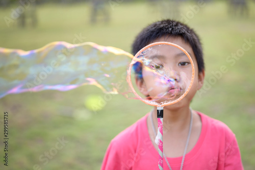 Cute Asian Kid making soap bubbles outside, summer time.