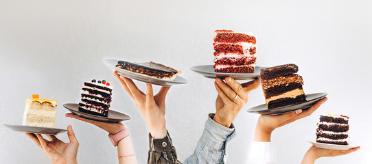 Concept for cafe or bakery with desserts: plates with different cakes in people's hands, place for your text