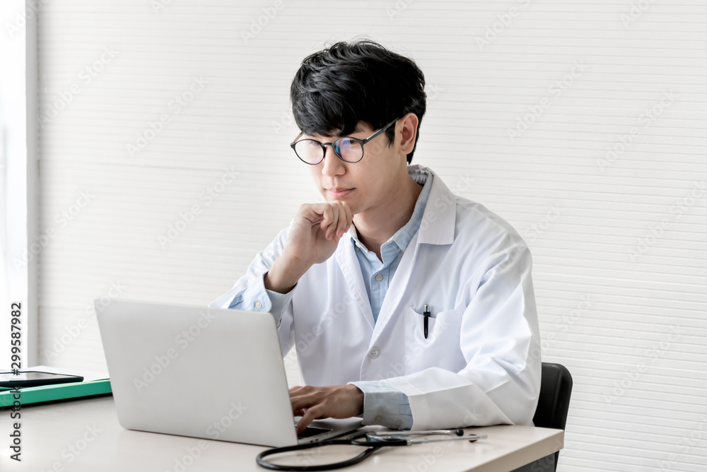 The doctor is using a notebook computer, In search of information And write a report about the patien's condition, on the desk at workplace with white background, to health care and insurance concept. The doctor is using a notebook computer, In search of information And write a report about the patien's condition, on the desk at workplace with white background, to health care and insurance concept.