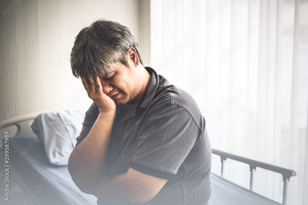 An Asian middle aged man Sitting on a patien's bed Is suffering from stress From their own illness the cause is obesity Causing diabetes Grease and clogging, to health care and insurance concept. An Asian middle aged man Sitting on a patien's bed Is suffering from stress From their own illness the cause is obesity Causing diabetes Grease and clogging, to health care and insurance concept.