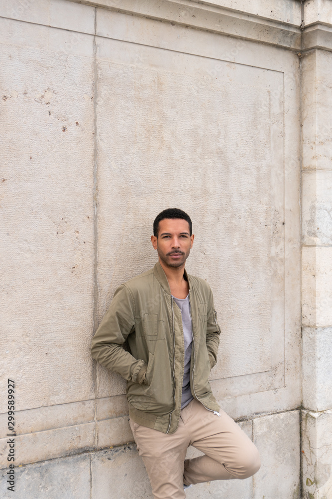Obraz premium Young man leaning against wall with hands in pockets
