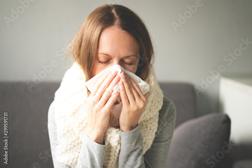Disease. Home treatment. A woman is sick at home, runny nose and flu. Warmly dressed and covered with a blanket. Blows her nose into a napkin, runny nose. Infection, epidemic, bacillus carrier