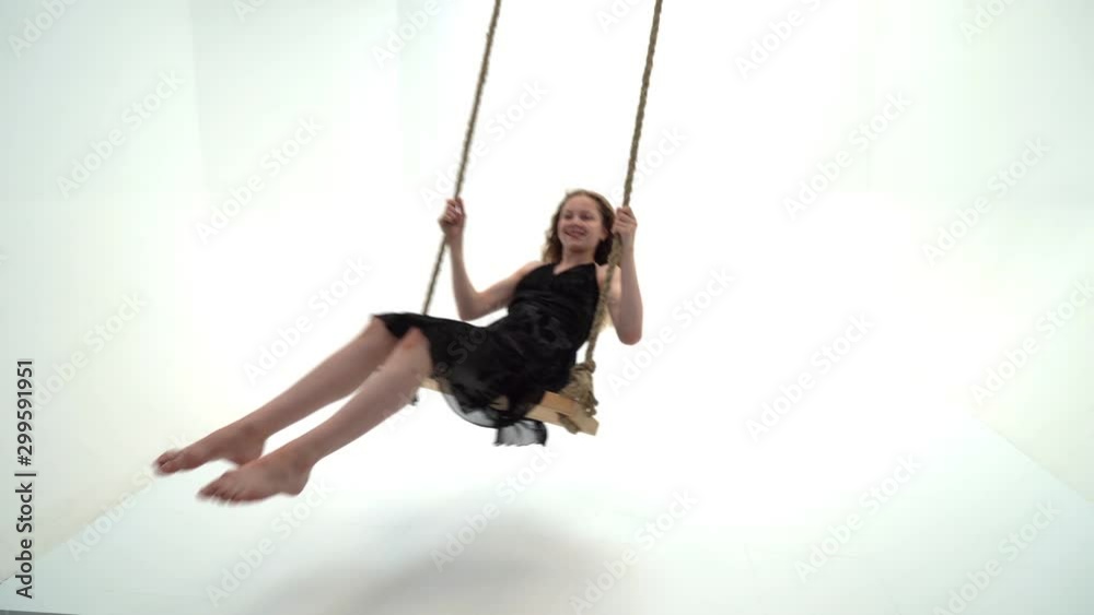 A little girl is swinging on a swing with a teddy bear.