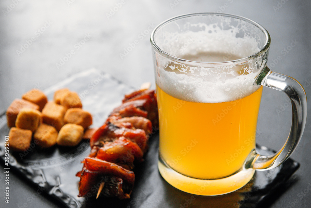 1 mug of light beer with foam with snacks on a dark background 1 mug of light beer with foam with snacks on a dark background