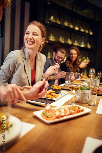 Photography Charming smiling caucasian blonde sitting in restaurant, eating dinner and chatting with friend