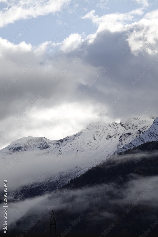 beautiful view to the alps with fog, clouds and fresh snow on the mountains in autumn