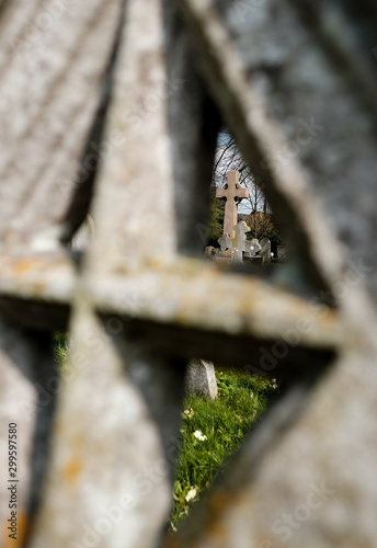 Abstract view of a very old churchyard with a distant gravestone seen through a nearby cross shaped grave. photo