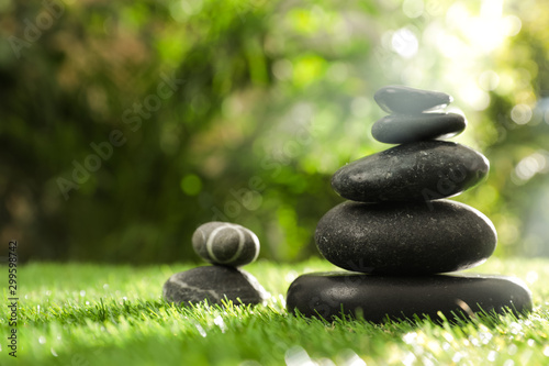 Stacks of stones on green grass against blurred background  space for text. Zen concept