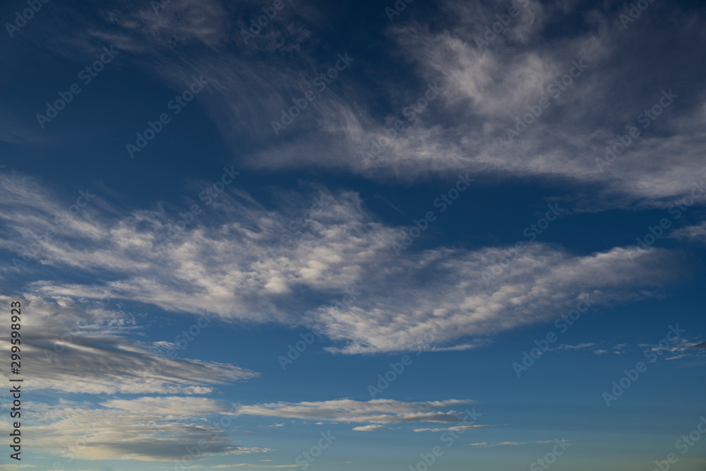 White sunset clouds painted across a deep blue sky showcasing a beautiful background on the Alberta prairies in big sky country. White sunset clouds painted across a deep blue sky showcasing a beautiful background on the Alberta prairies in big sky country.