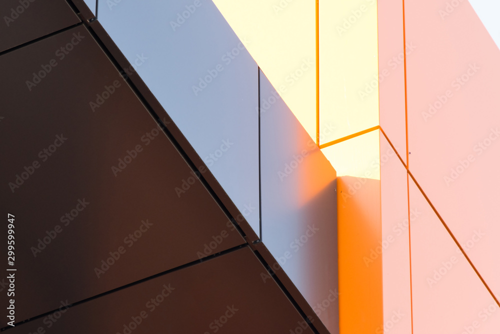 Geometric color elements of the building facade with planes, lines, corners with highlights and reflections for an abstract background and texture of gray, orange colors. Place for text - obrazy, fototapety, plakaty 