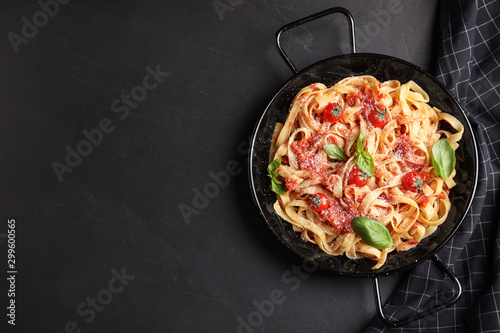 Tasty pasta and napkin on black table, flat lay. Space for text photo