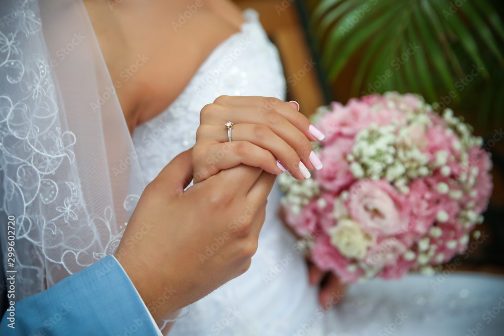 hands of the bride and groom on the background of a wedding bouquet