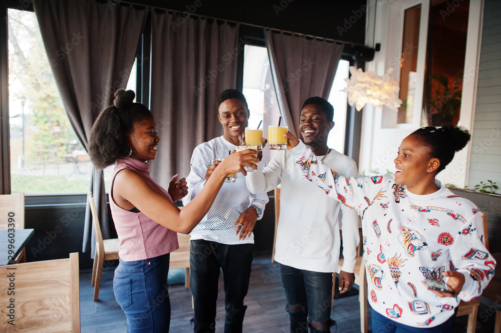 Happy african friends sitting and chatting in cafe. Group of black peoples meeting and cheers in restaurant. Happy african friends sitting and chatting in cafe. Group of black peoples meeting and cheers in restaurant.