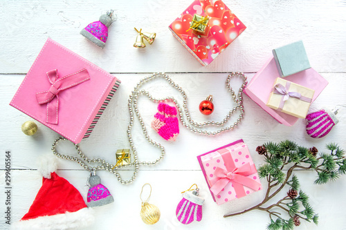 Christmas background top view. Pink and red gift boxes. Coniferous branches and Christmas toys on a background of a white wooden board. New Year 2020