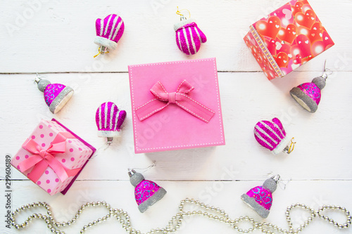 Christmas background top view. Pink and red gift boxes. Coniferous branches and Christmas toys on a background of a white wooden board. New Year 2020