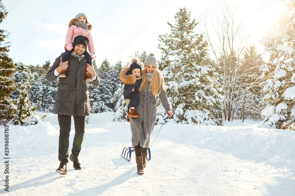 Happy family sledding in the park in winter. - obrazy, fototapety, plakaty 
