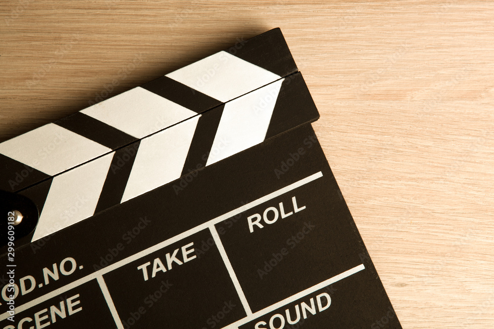 Naklejka premium black movie clapper on a wooden background top view