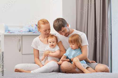 Happy family with baby on bed smiling in room.