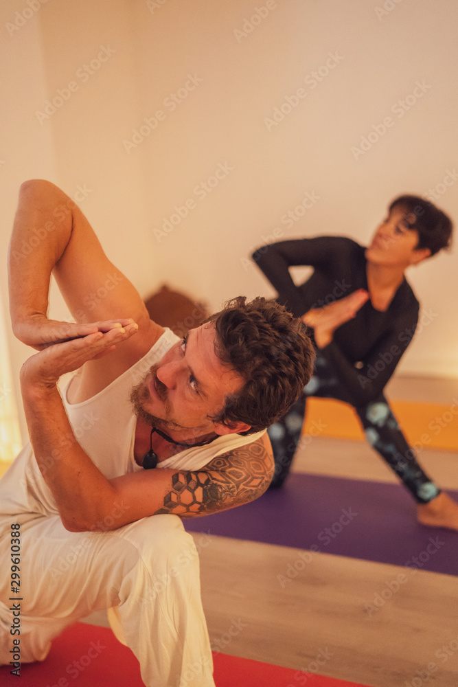 Fototapeta premium couple practicing yoga in a room lit by candlelight