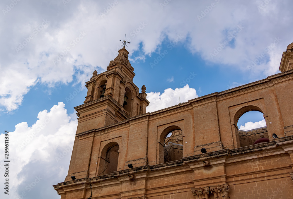 St Paul's Cathedral bell tower shot from low angle against blue cloudy sky, in Mdina, Malta.