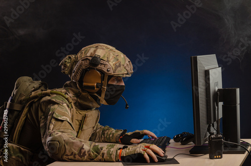 military in uniform sitting at a computer conducts cyber warfare photo