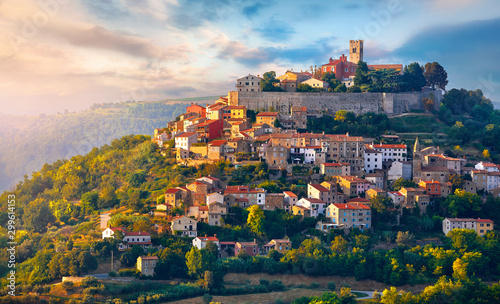 Antique city Motovun Croatia Istria. Picturesque panorama age-old village at hill with pink cloud and sunny light and authentic home with red tegular roof and green vineyard garden. photo