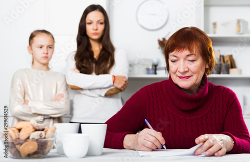 Senior woman writing letter, daughter and granddaughter dissatisfied