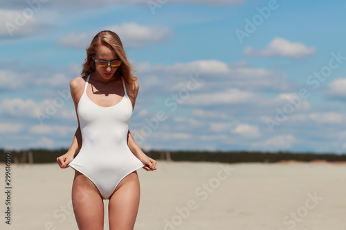 Canvas Print Confident sexy woman in seductive posture pulling swimwear on beach
