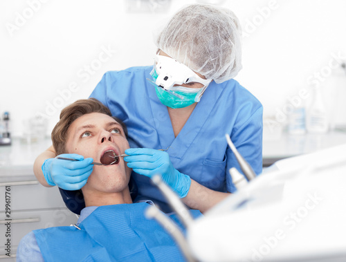 Dentist female in uniform is examinating of male in dental clinic