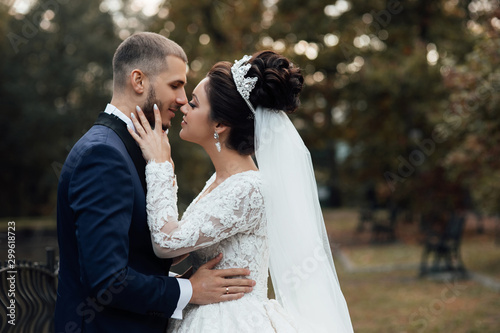 Bride and groom. Close-up of newlyweds smiling and caressing. Loving wedding couple. Lovely young couple in love glow with happiness together. Newlyweds smile at each other at wedding day. 