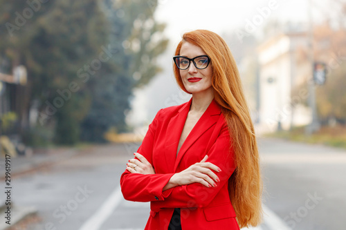 Fotografija beautiful girl with red hair dressed in a red business suit