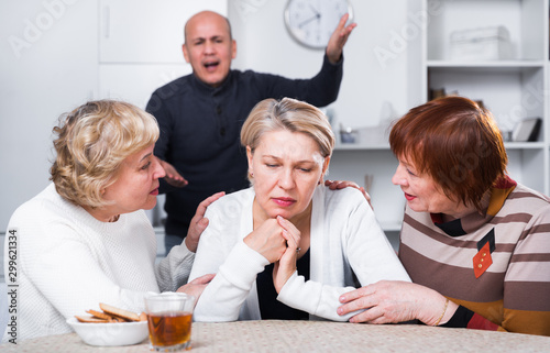 Mature woman is sitting upset and her girlfriends are expressioning understanding to she