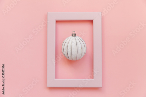 Simply minimal composition winter objects ornament ball in pink frame isolated on pink pastel trendy background. Christmas New Year december time for celebration concept. Flat lay top view photo