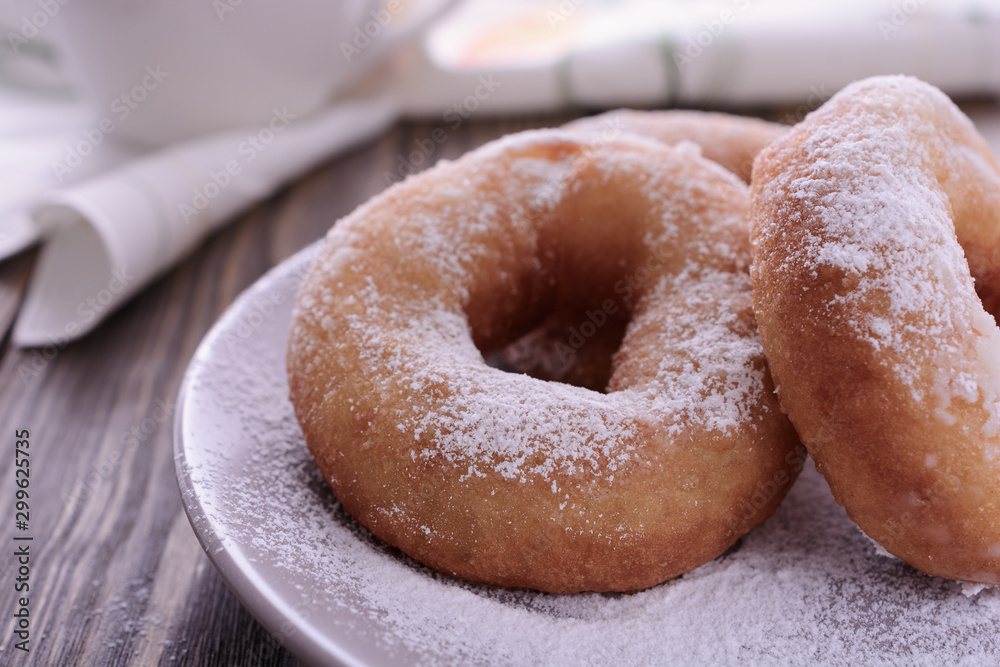 Doughnuts with sugar powder on a wooden table.  Traditional hot fried donuts.
