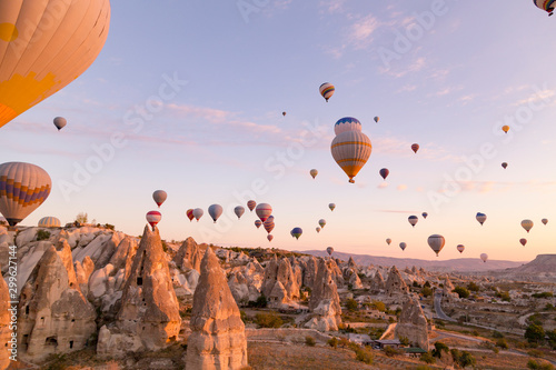 Bright soft pink light of sunrise as many balloons fly above Cappadocia Turkey. View of a valley full of hot air balloons floating at sunrise.
