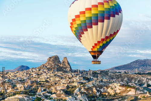 A single bright hot air balloon floats over the cave homes and town in Cappadoccia, Turkey.