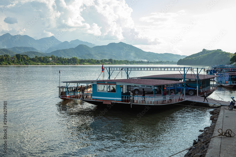 Traditional Ferry Boat on the Mekong River and mountains view in Luang Prabang, Laos.