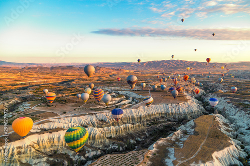 Bright and colourful hot air balloons at sunrise floating along the valleys and mountains in Cappadocia, Turkey