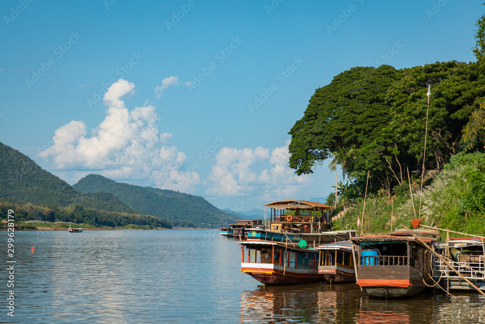 Naklejka premium Traditional Long Boat on the Mekong River and mountains view in Luang Prabang, Laos.