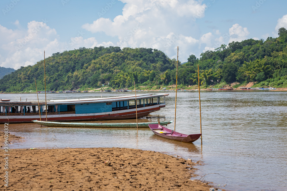 Fototapeta premium Traditional Long Boat on the Mekong River and mountains view in Luang Prabang, Laos.