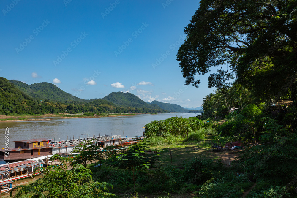 Traditional Long Boat on the Mekong River and mountains view in Luang Prabang, Laos.