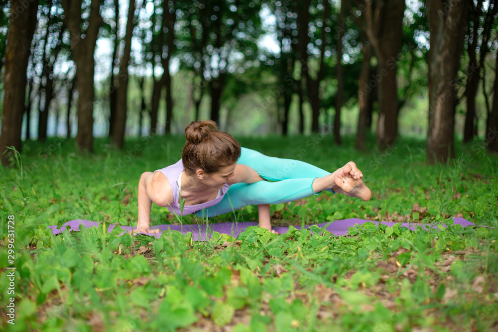 A young sports girl practices yoga in a quit green summer forest, yoga assans posture. Meditation and unity with nature A young sports girl practices yoga in a quit green summer forest, yoga assans posture. Meditation and unity with nature