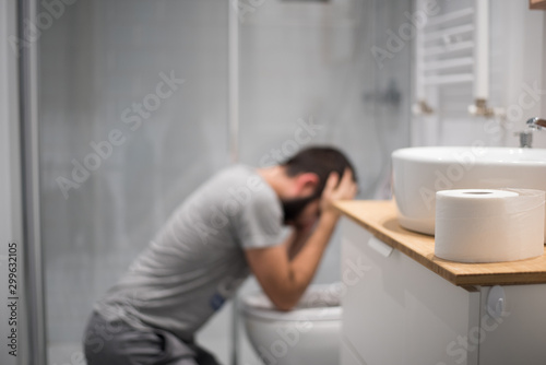 Hombre en el baño intentando vomitar en el water