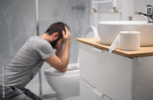 Hombre en el baño intentando vomitar en el inodoro photo
