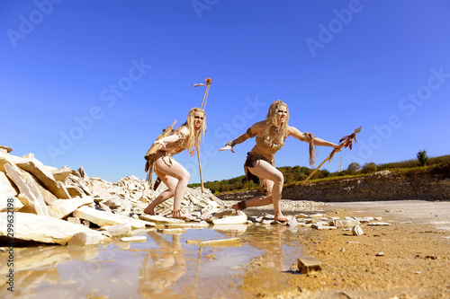 Two girls are dressed as neanderthal warriors. They are covered with mud,filth and dirt and are seen in a stone quarry.