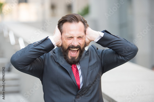 Portrait of shouting businessman covering his ears with hands