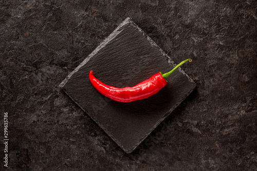 Single red dried banana pepper on a dark gray slate