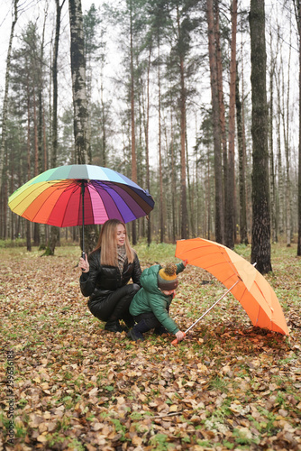 a beautiful Caucasian mother and little child having fun in autumn Park, walking with umbrella